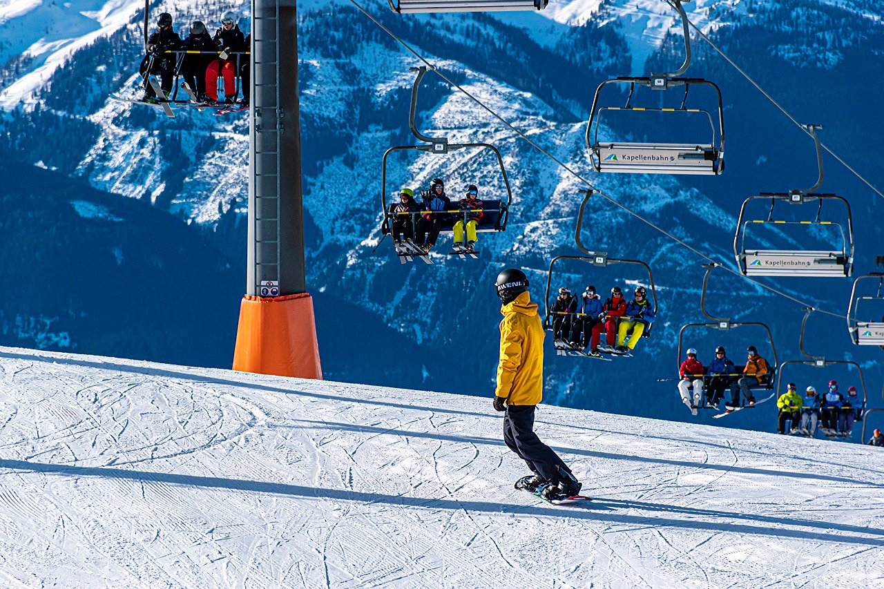 man snowboarding down a mountain with chairlift