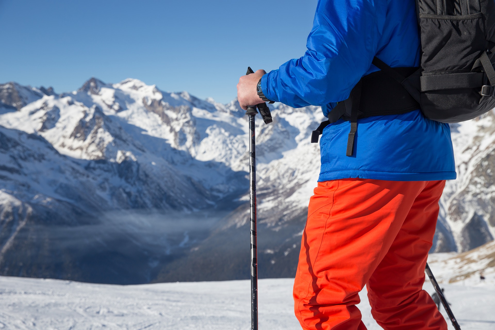 man with ski poles at the top of a mountain 