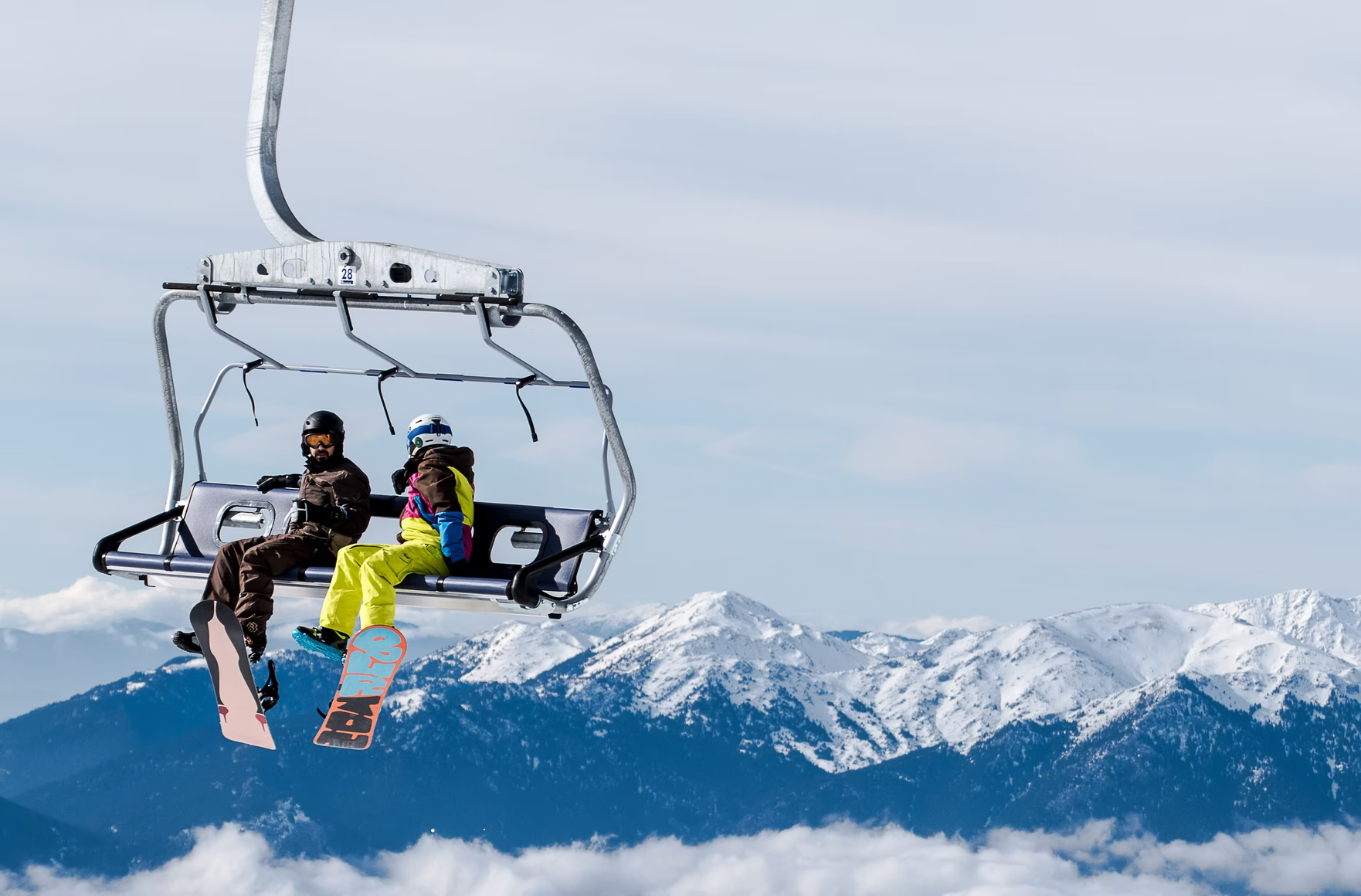 ski resort chair lift with 2 passengers with mountains in the background