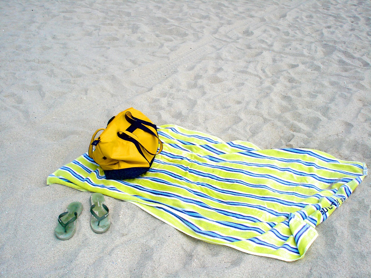 towel, drybag, and flip flops on the beach