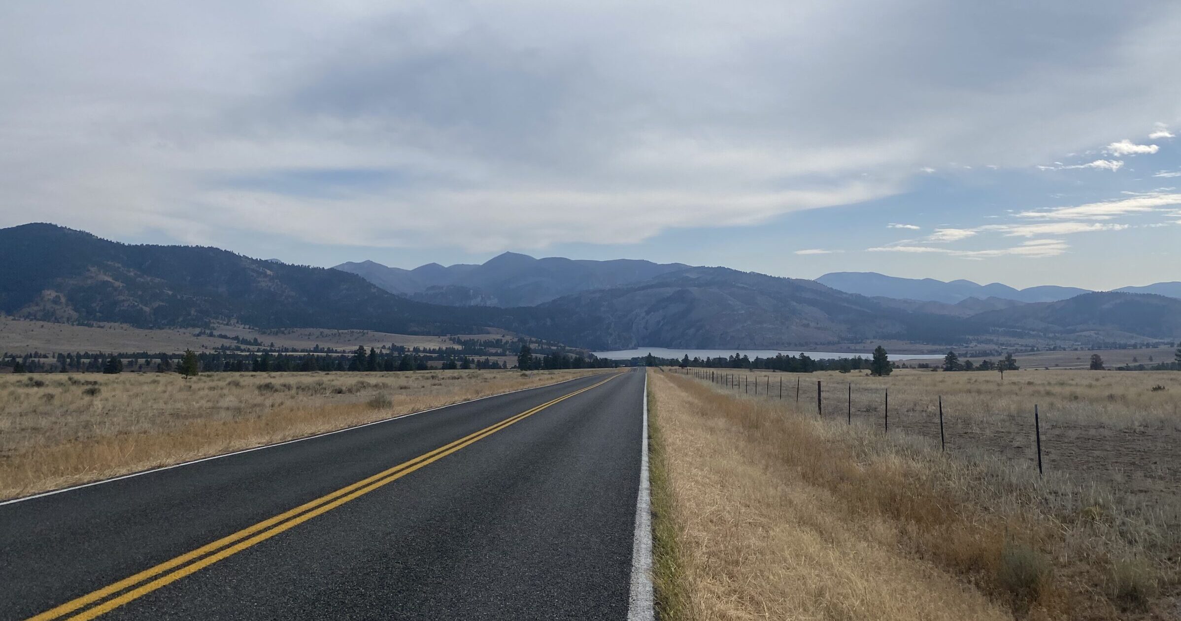 Montana road with pavement and mountains in the distance- 4 day montana itinerary