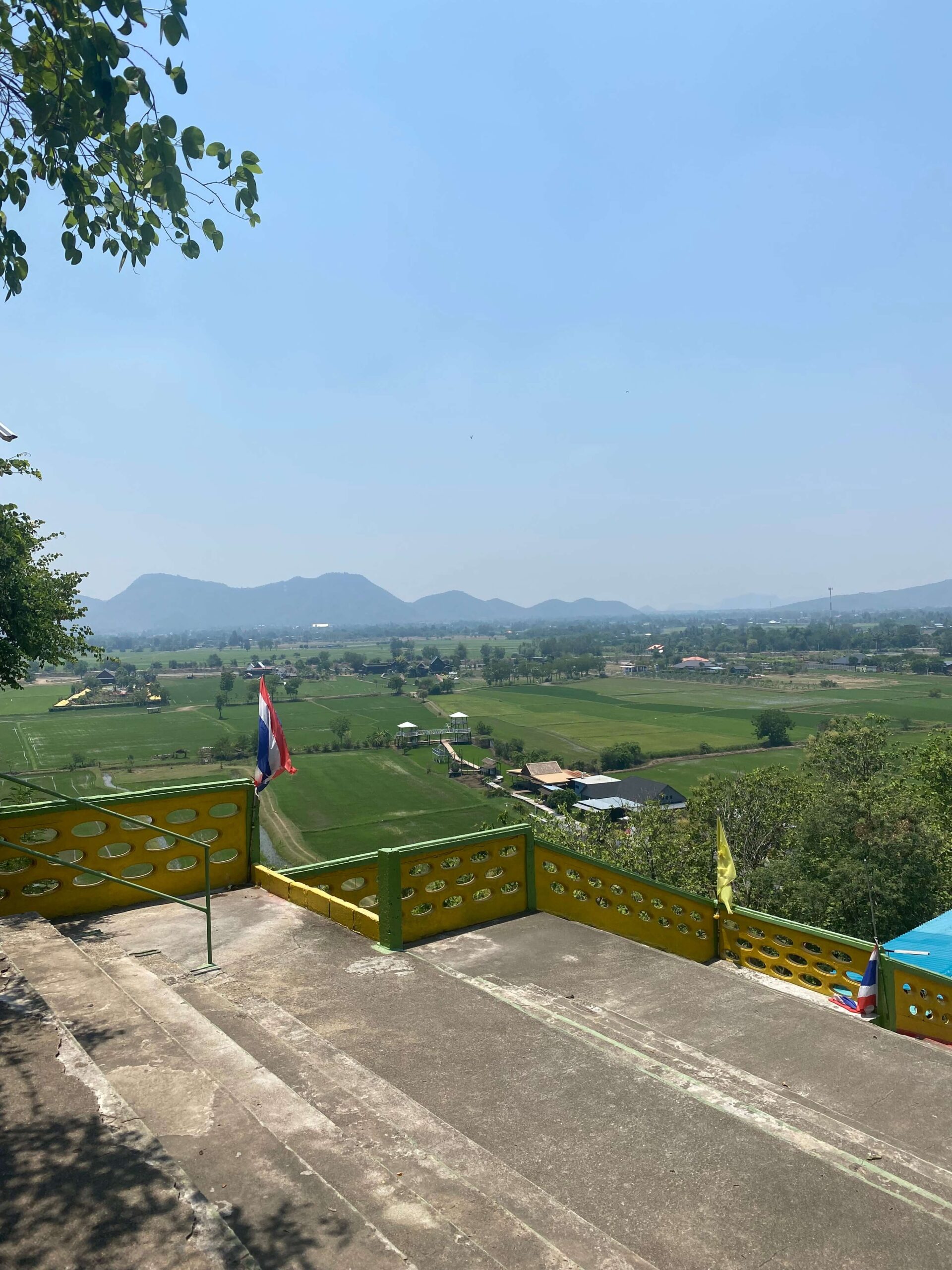 viewponit of lush green fields in Kanchanaburi with mountains in the distance - beautiful places in thailand