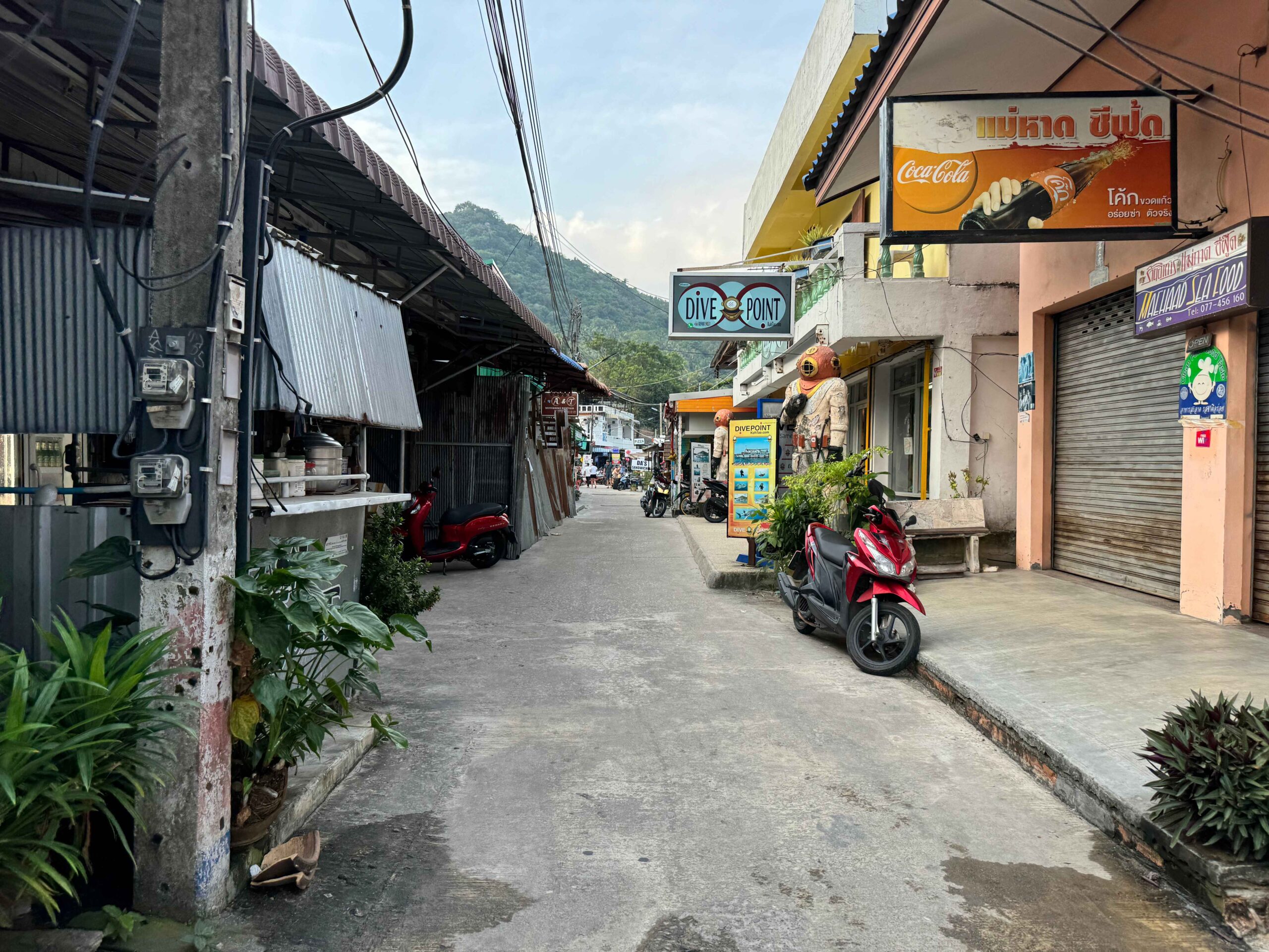 downtown Koh Tao street with shops and a motorbike