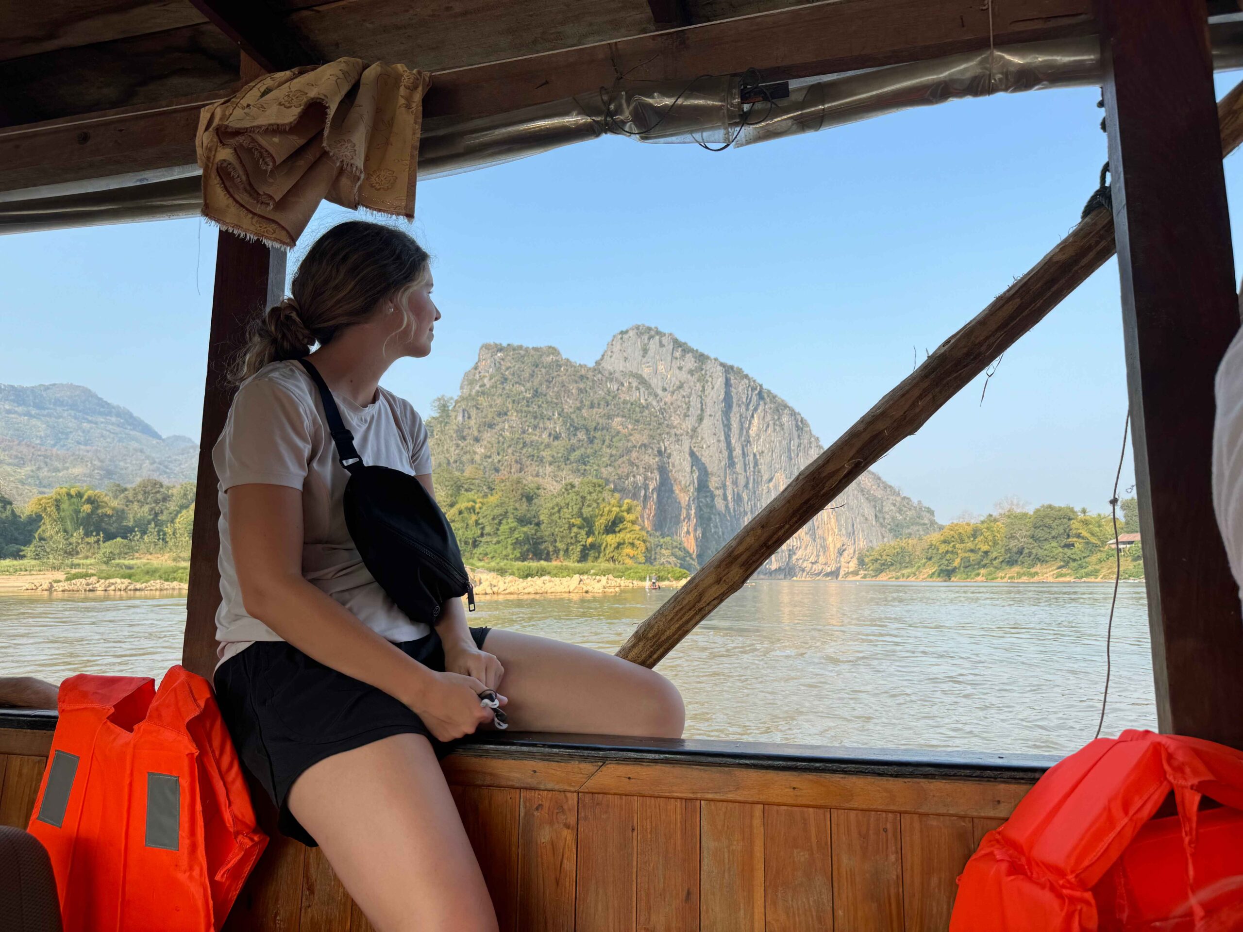 slow boat to luang prabang where i am looking out of the window with a mounain in the background