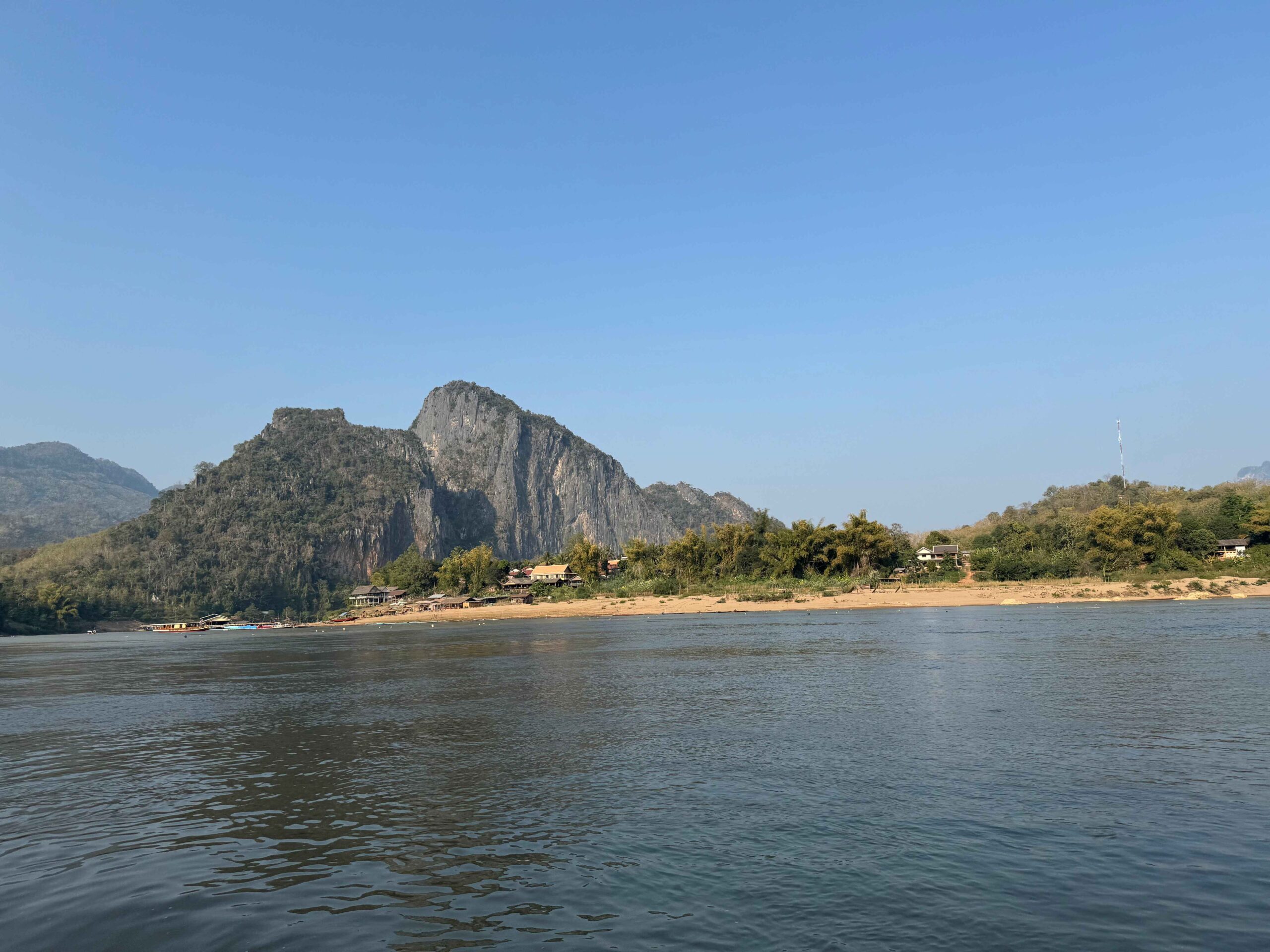 view of a mountain and beach from the slow boat on the water