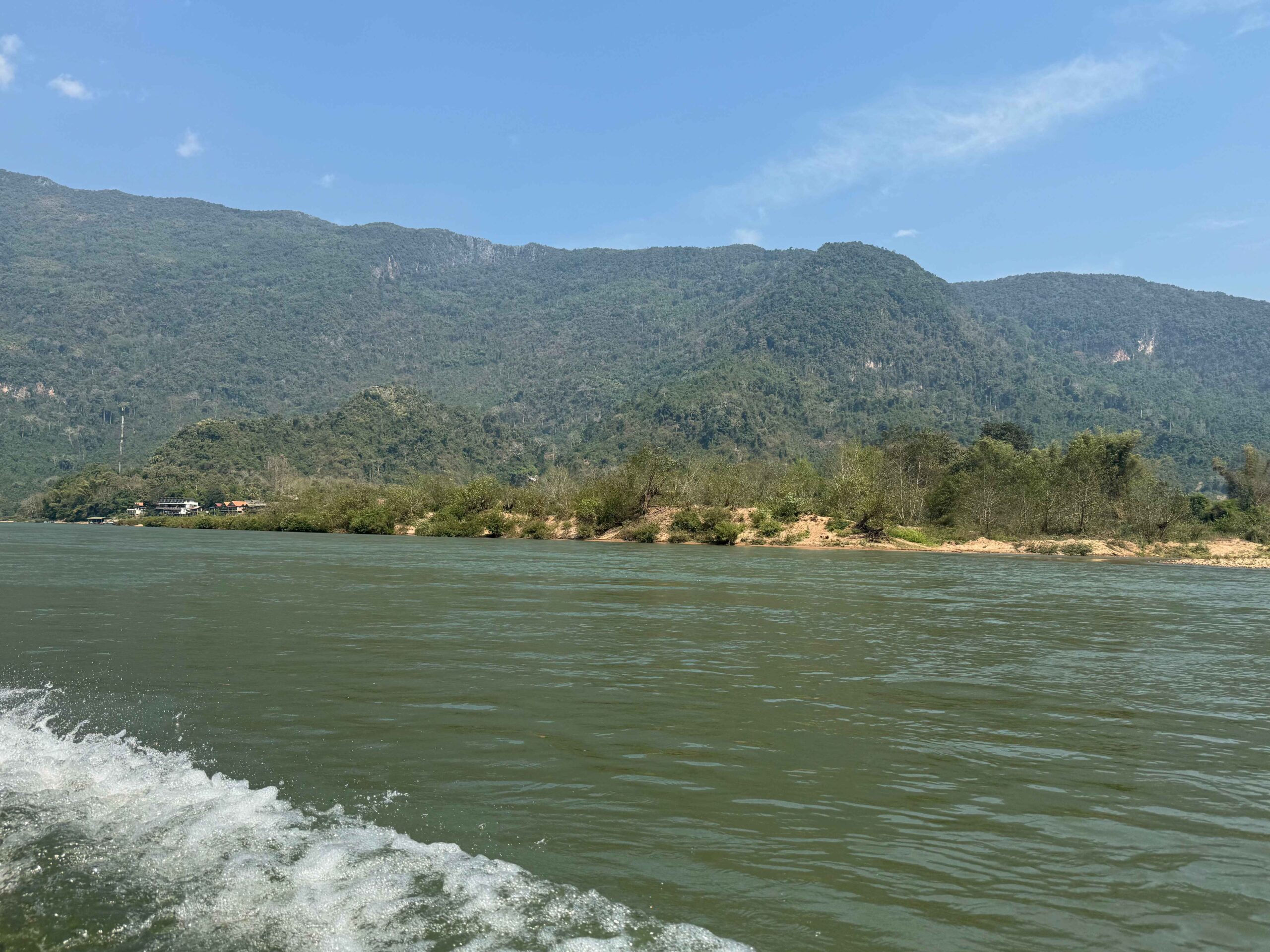 a boat ride on a river, the water is green and there are green mountains in the background