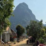 muang ngoy things to do - small village with dirt road and mountain in the background