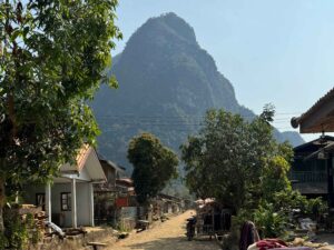 muang ngoy things to do - small village with dirt road and mountain in the background