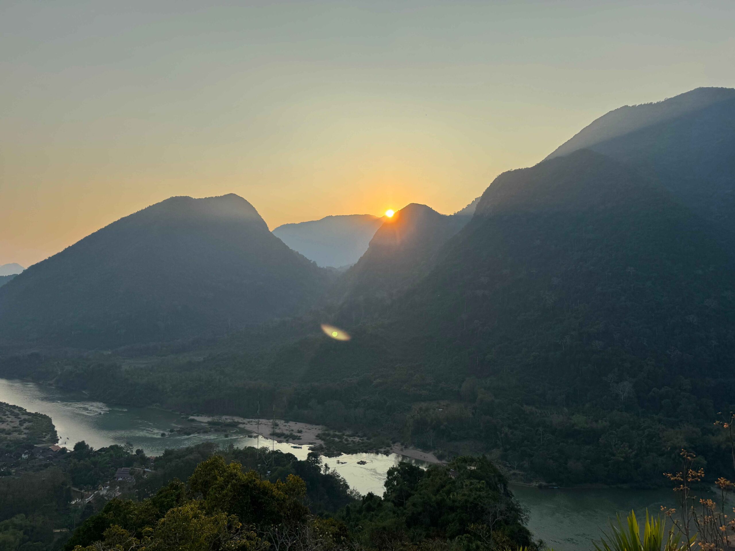 things to do in Muang Ngoy, view from the top of a mountain viewpoint while the sun is setting in the smokey air