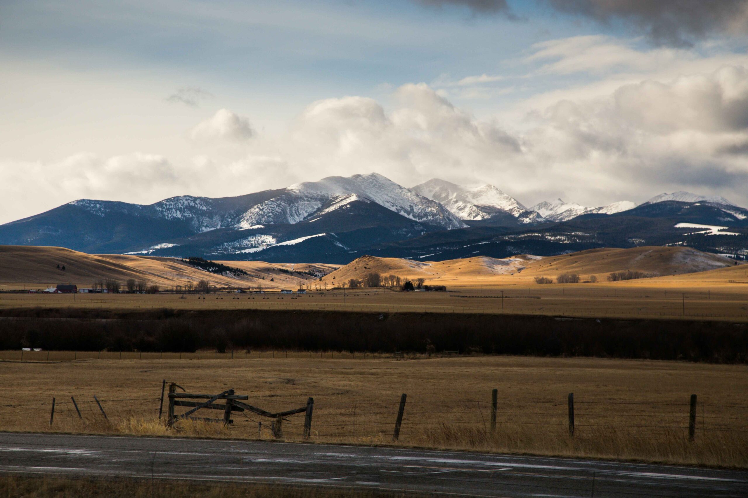 rocky mountains from the side of the road with a wooden fencer